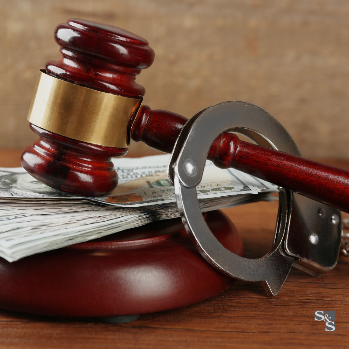 A gavel, handcuffs and banknotes arranged on a wooden desk, representing bail in criminal proceedings.
